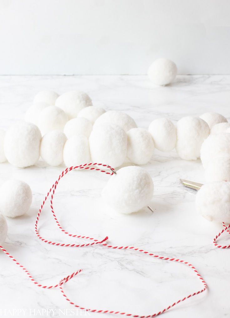 white pom - poms and twine on a marble table with red string