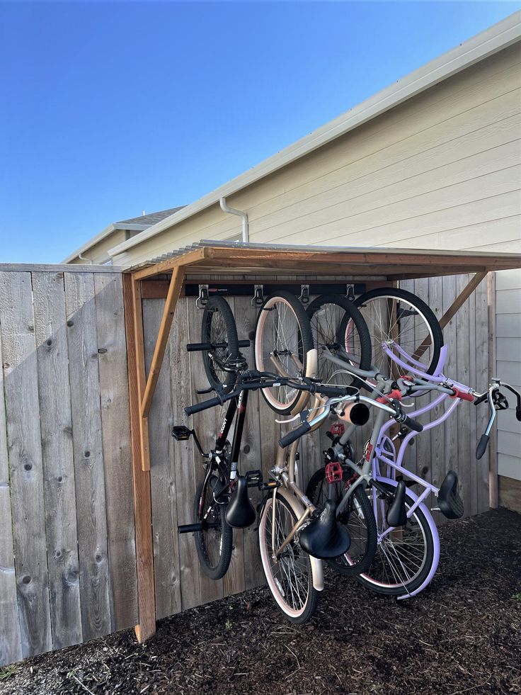 there is a bike rack in the back yard with many bikes on it and two bicycles hanging from the roof