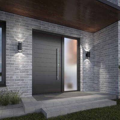 the front door to a modern house is lit up by two lights on either side