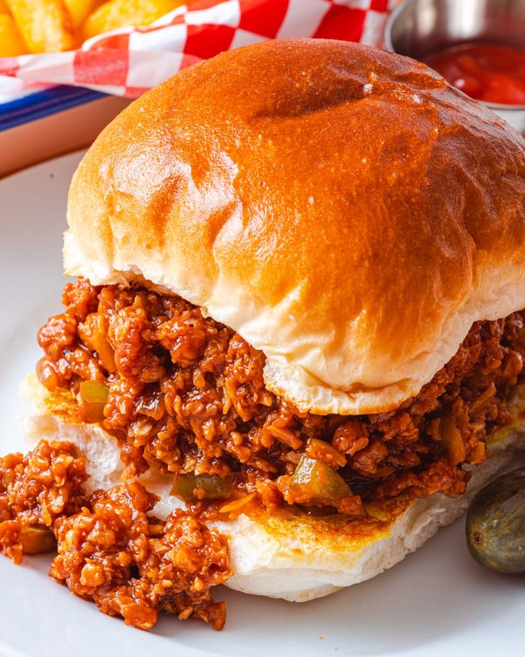 a sloppy joe sandwich with pickles on the side