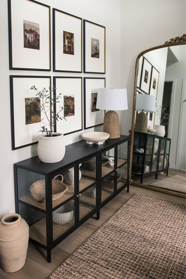 a living room with pictures on the wall and a table in front of a mirror