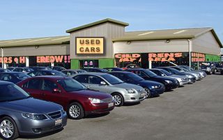 several cars parked in front of a used car dealership with the words used cars written on it