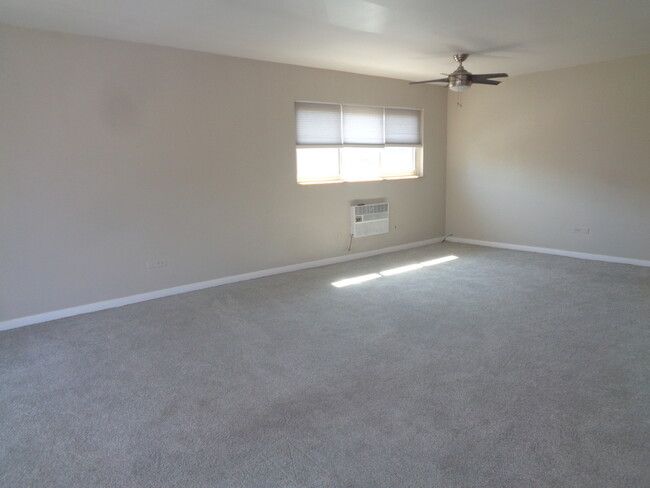 an empty living room with no one in it and a ceiling fan on the far wall