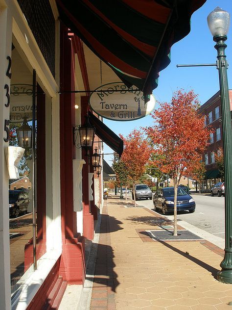 an empty sidewalk in front of a store with cars parked on the side walk next to it