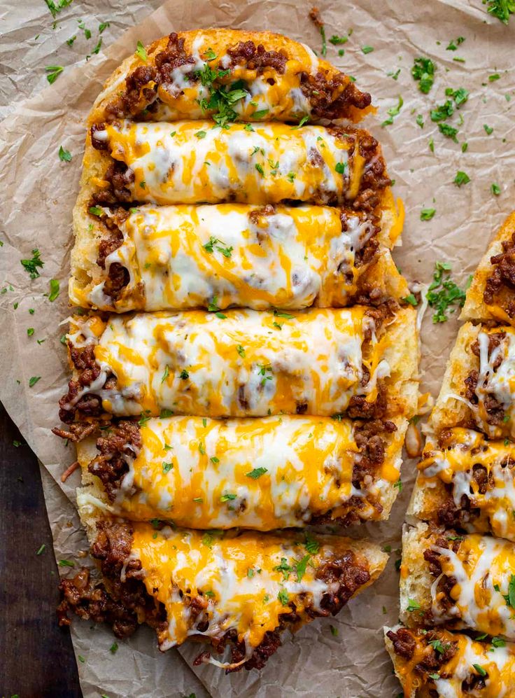 several pieces of pizza with cheese and meat on them sitting on top of wax paper