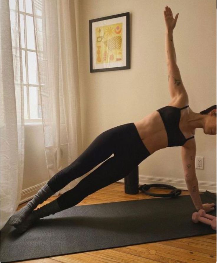 a woman is doing yoga on a mat in front of a window with her leg up