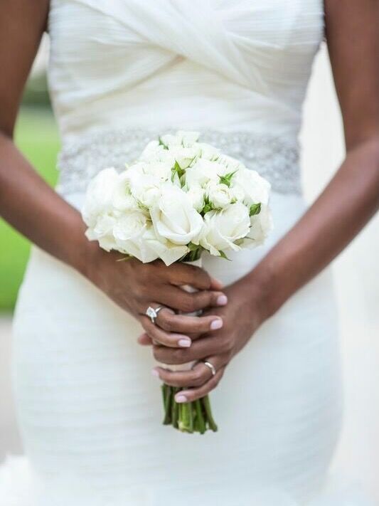 a woman in a wedding dress holding a bouquet of white flowers with her hands on her hips