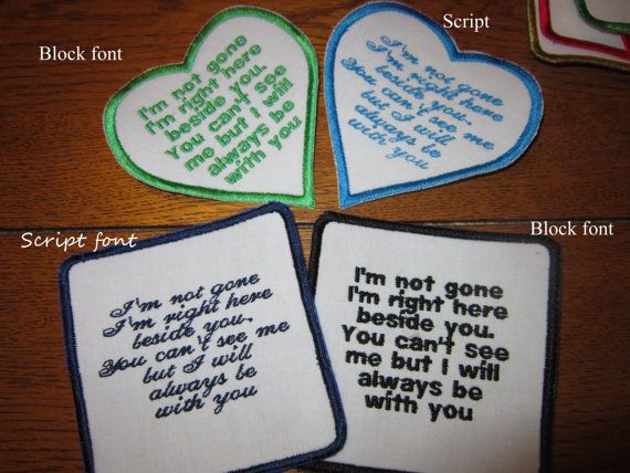 three embroidered hearts with words on them sitting on top of a wooden table next to each other