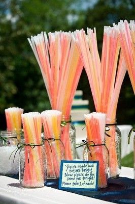 there are many pink and yellow straws in mason jars on the table with a sign