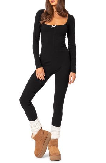 A stretchy ribbed design adds to the endless comfort of this cozy jumpsuit designed with long sleeves and a wide scoop neckline detailed with a dainty bow. Pull-on style Scoop neck Long sleeves 45% polyester, 45% rayon, 10% spandex Machine wash, dry flat Imported Black Stretch Ribbed Jumpsuits And Rompers, Fitted Black Ribbed Jumpsuit, Long Sleeve Bodysuit For Loungewear In Fall, High Stretch Ribbed Bodysuit For Loungewear, High Stretch Unitard For Loungewear In Fall, Trendy Fall Loungewear Bodysuit, Long Sleeve Winter Bodysuit For Loungewear, Winter Long Sleeve Bodysuit For Loungewear, Long Sleeve Ribbed Jumpsuits And Rompers For Loungewear