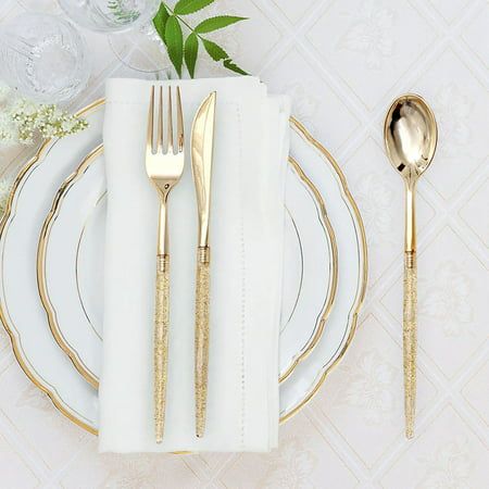 a white plate topped with goldware next to a silver fork and knife on top of a table