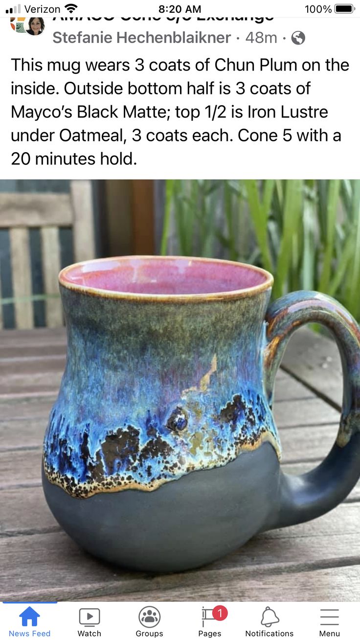 a coffee mug with blue and pink glaze on it sitting on a wooden table