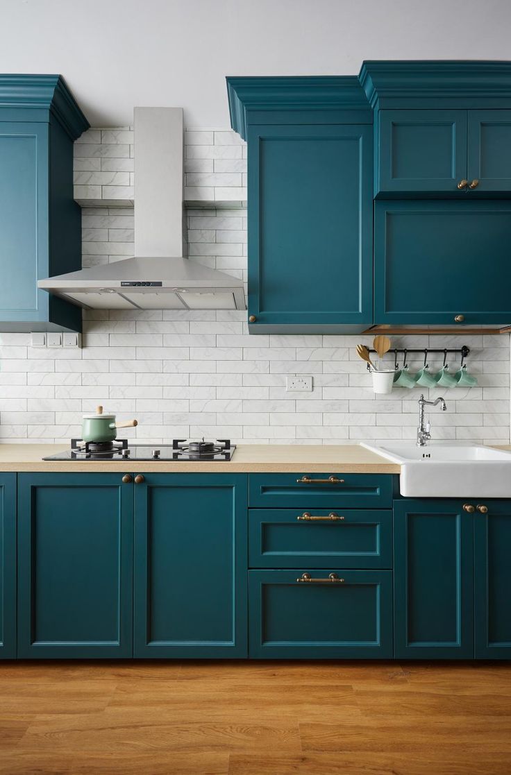 a kitchen with teal cabinets and white tile backsplash