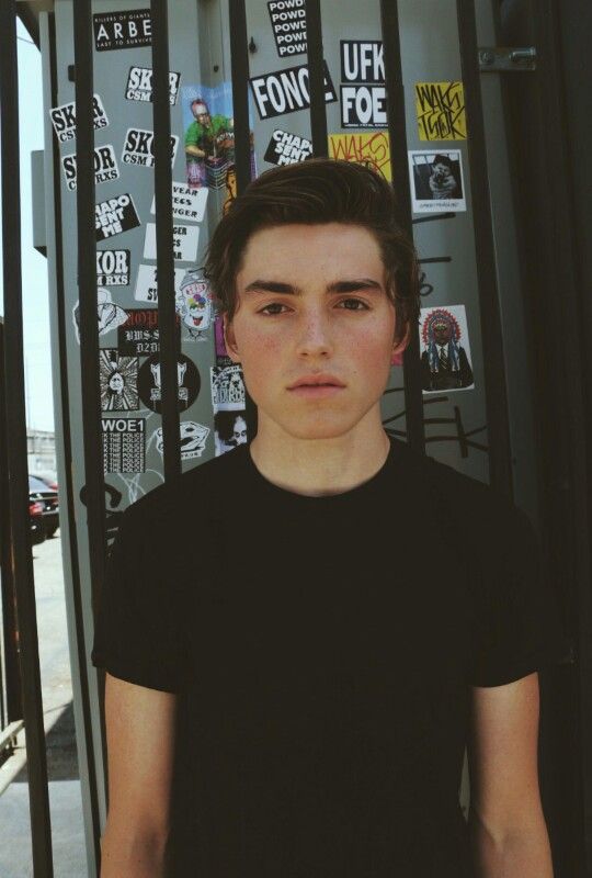 a young man standing in front of a wall with stickers on it