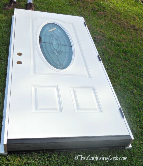 a white door sitting in the grass next to a person standing on it's side