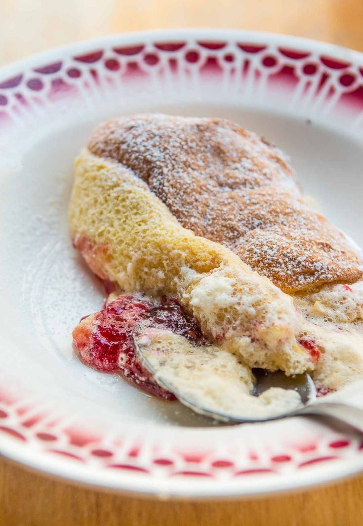 a dessert on a plate with powdered sugar and strawberries in the foreground