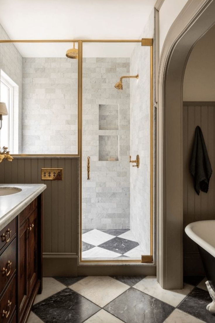 a bathroom with a black and white checkerboard floor, gold fixtures and a walk in shower