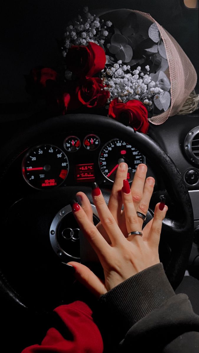 a woman's hand on the steering wheel of a car with roses and pearls