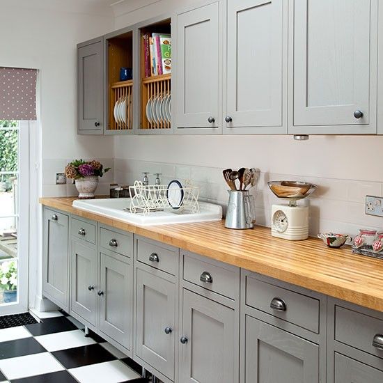 a kitchen with gray cabinets and black and white checkered flooring on the floor