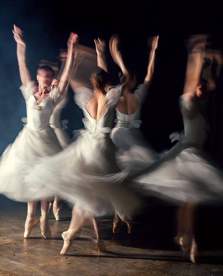 several ballet dancers in white tutu skirts are dancing with their hands up and arms outstretched