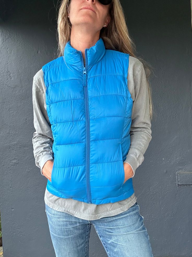 Stay toasty and on trend with the Beacon 2 Vest! This ultra-cozy puff vest has a high-neck design and a storage pouch for all your essentials. Keep warm and snug whether you’re out and about or just lounging around. Feeling fly has never been so easy! Casual Puffer Jacket For Travel, Winter Functional Solid Vest, Functional Solid Winter Vest, Functional Solid Color Winter Vest, Outdoor Puffer Vest Jacket Sleeveless, Blue Winter Vest For Outdoor Activities, Blue Vest For Outdoor Winter Activities, Cold Weather Solid Puffer Vest, Solid Color Puffer Vest For Cold Weather