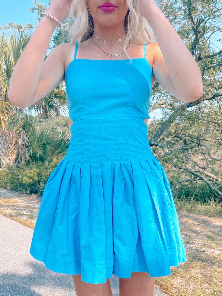 Our Twisted Teal Dress is an electric blue beauty featuring adjustable straps, side cutouts, a pleated fit, and an open tie back. Model is wearing a size small. Lined. content: 65% cotton, 35% linen Blue Sundress With Adjustable Straps For Spring, Blue Mini Dress With Adjustable Straps For Spring, Blue Dresses With Adjustable Straps And Strappy Back, Blue Dress With Adjustable Straps And Strappy Back, Blue Square Neck Sundress With Adjustable Straps, Blue Sundress With Adjustable Straps And Square Neck, Blue Linen Mini Dress For Vacation, Chic Blue Sundress With Tie Straps, Fitted Pleated Summer Sundress