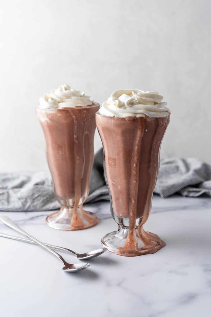 two glasses filled with chocolate milkshake and whipped cream