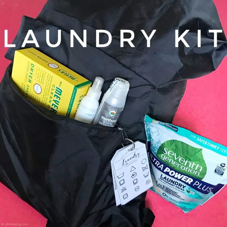 the contents of a laundry kit are neatly packed in a black bag on a pink surface