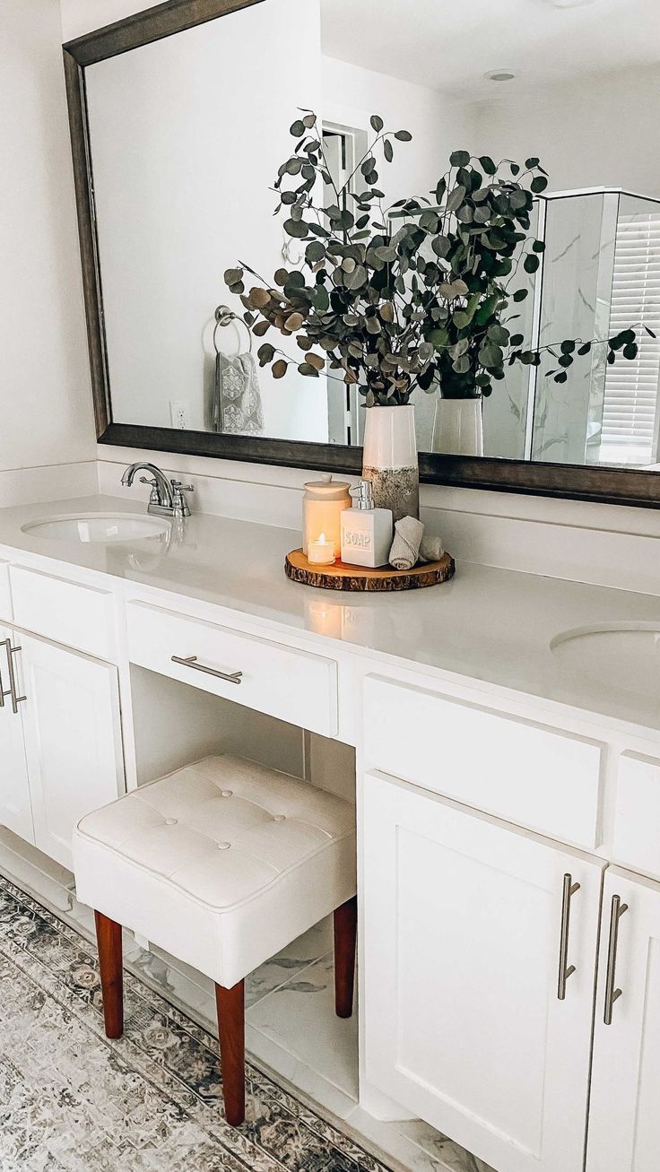 a bathroom vanity with a mirror, stool and plant on it in front of the sink