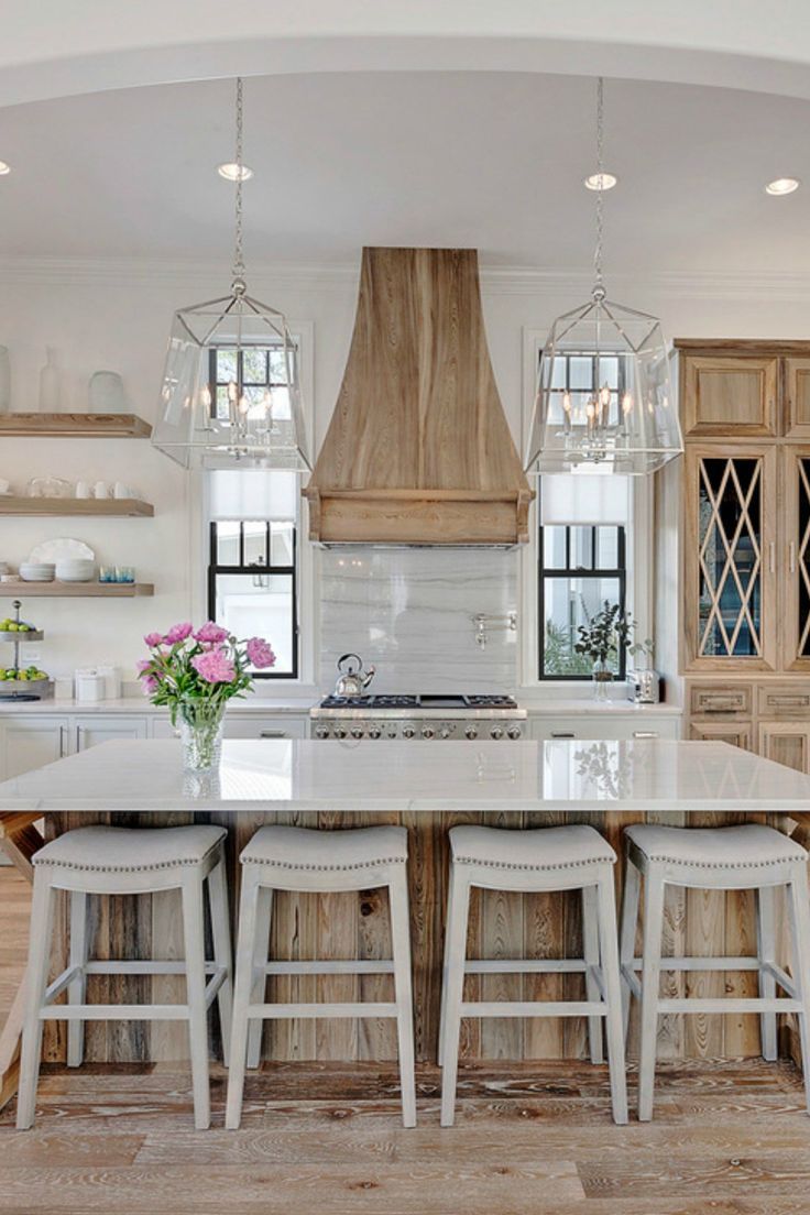 a kitchen with white counter tops and stools next to an island in the middle