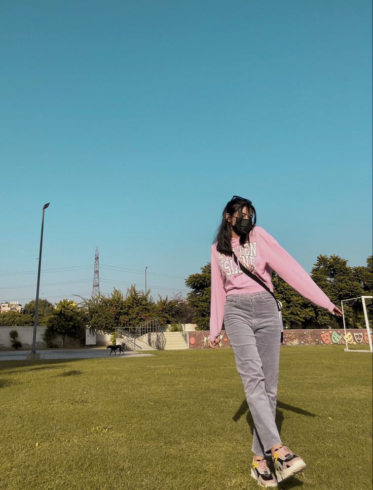 a woman in pink shirt and grey pants on skateboard