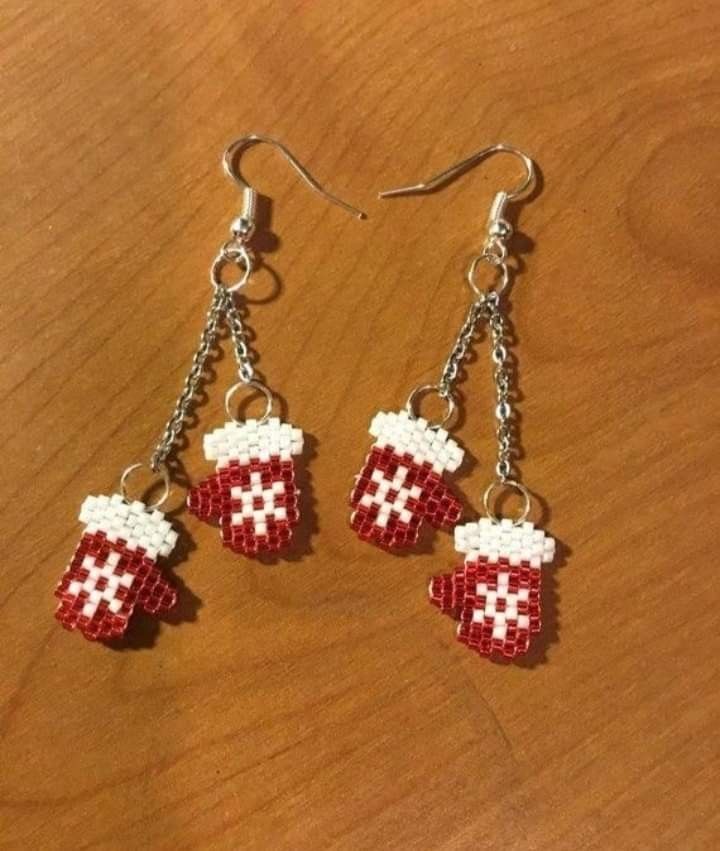 two red and white cup shaped beads hanging from silver chain earrings on a wooden surface