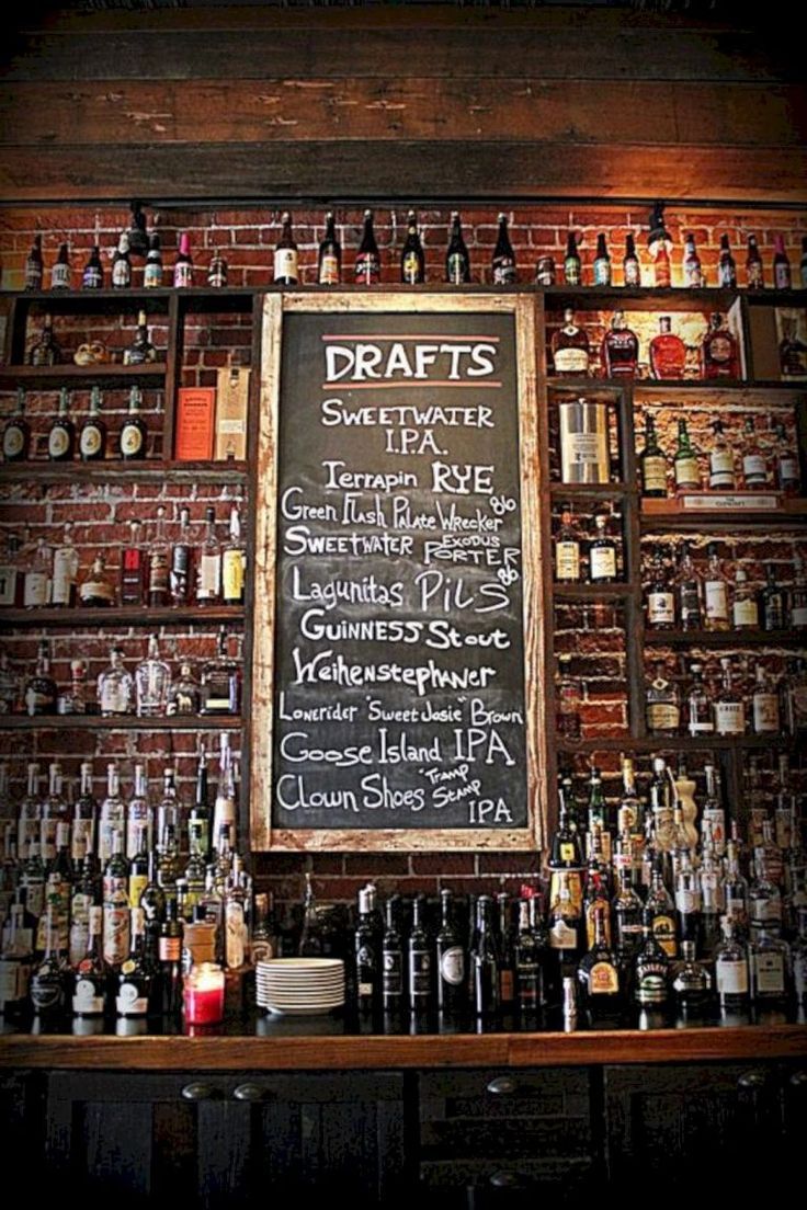 a bar with lots of bottles on the wall and a chalkboard sign above it