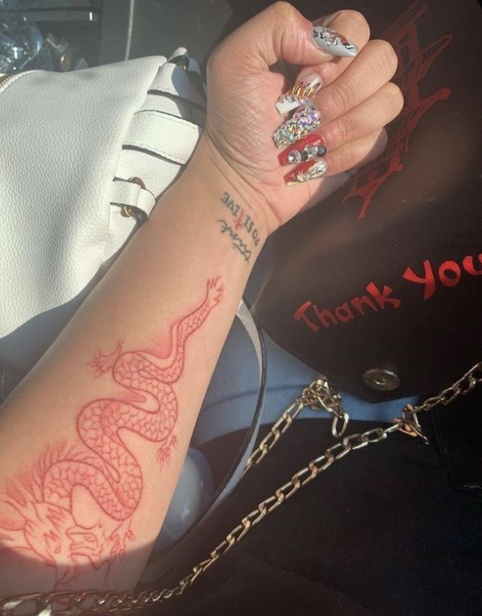 a woman's arm with a tattoo on it and a chain around her wrist