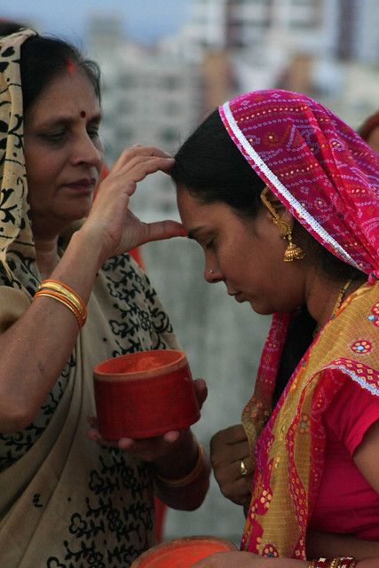 two women in sari are looking at something on the other side of her face