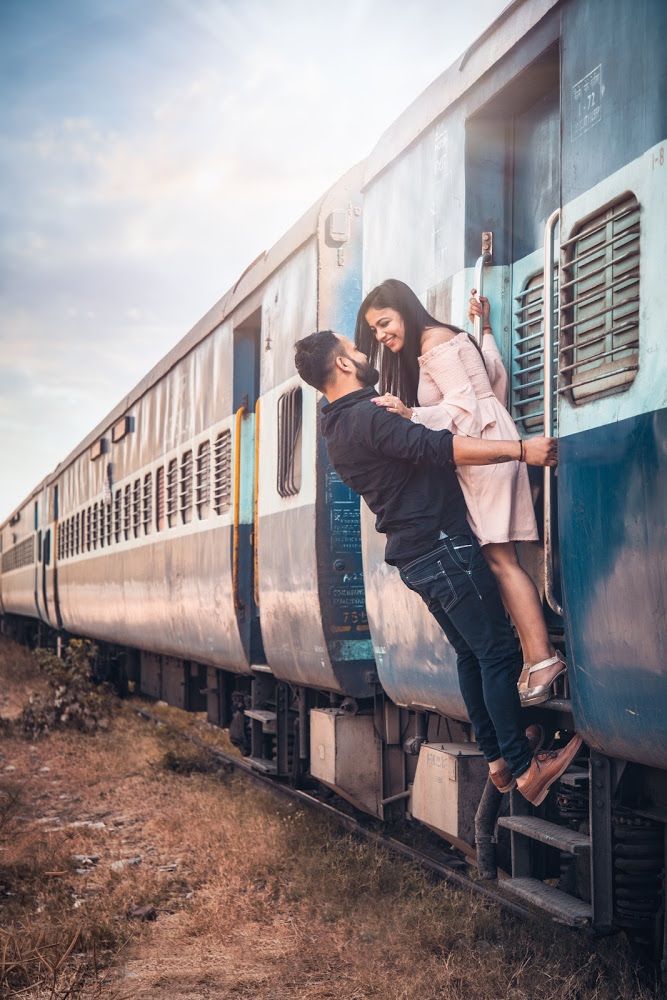 a man and woman standing on the side of a train car with their arms around each other