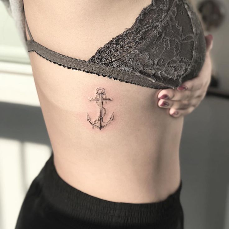 an anchor tattoo on the side of a woman's stomach is seen in this image