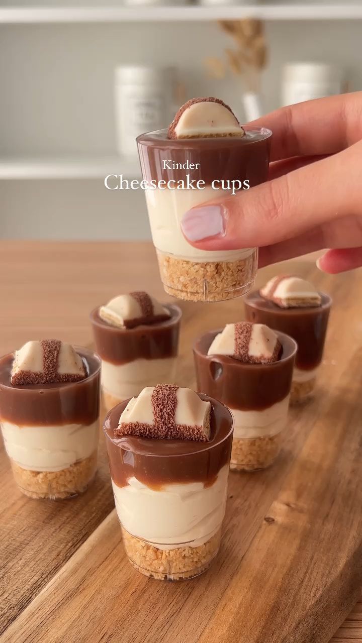 there is a person holding a cupcake in front of small desserts on a wooden tray