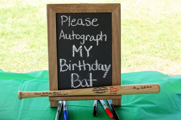 a chalkboard with writing on it and two baseball bats next to it, sitting on a green cloth