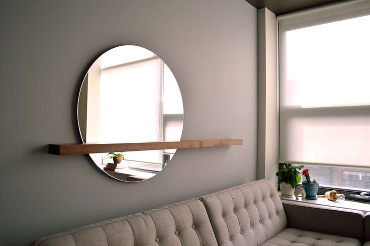 a couch sitting next to a window with a mirror on it's wall above it