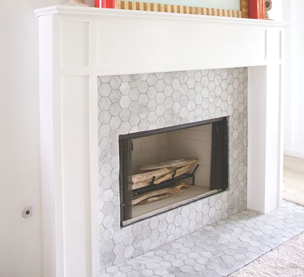 a white fireplace with an ornate design on the mantle