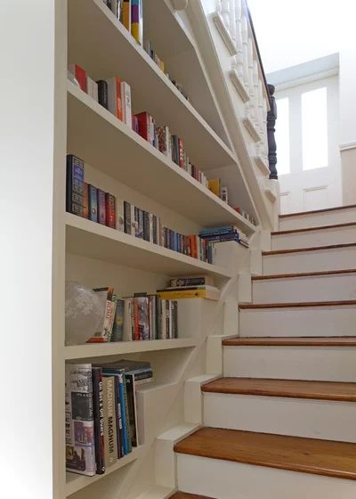 there are many books on the shelves next to the stairs