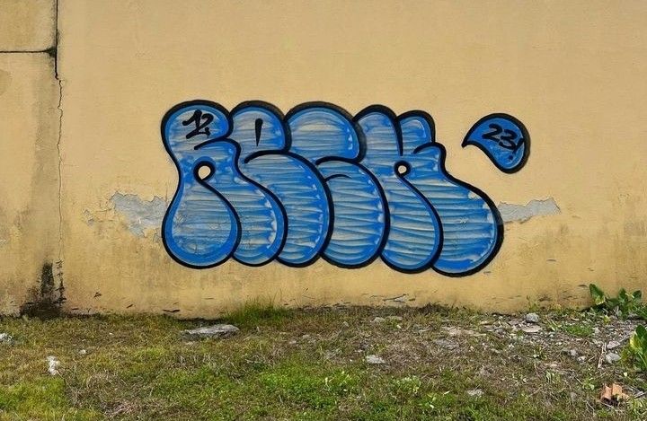 graffiti on the side of a building with blue spray paint and numbers painted on it