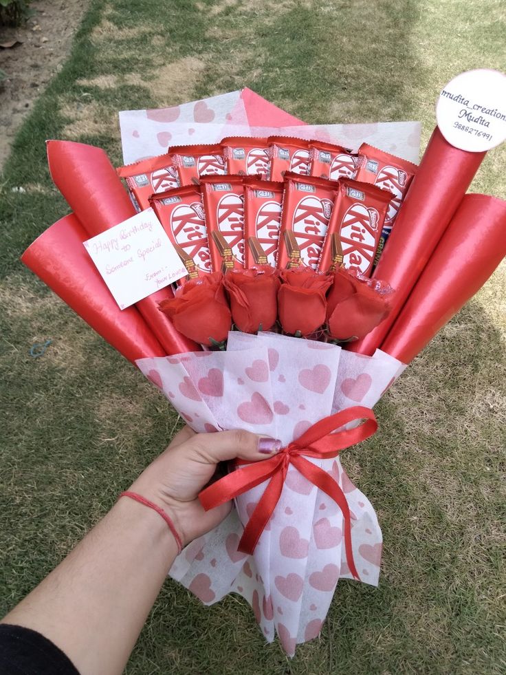 a person is holding a bouquet of chocolates and wrapped in red paper with hearts