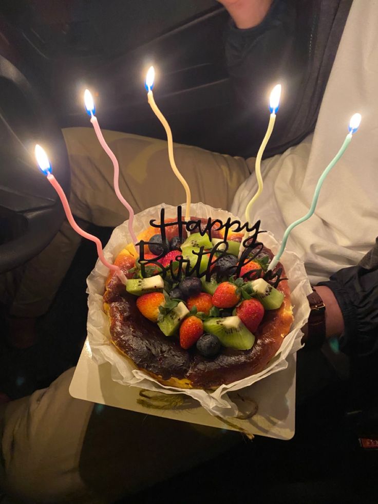 a man holding a birthday cake with lit candles