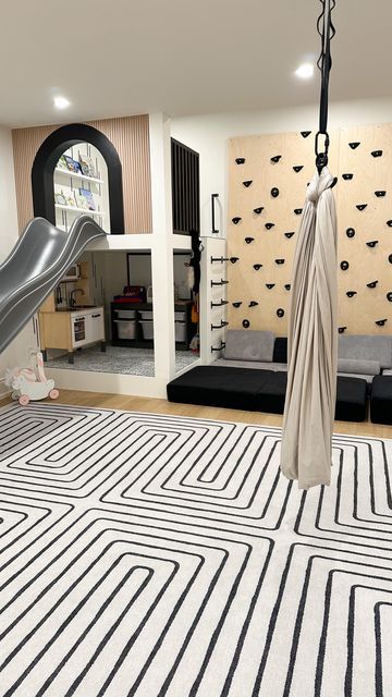 an indoor play area with slide and black and white rug