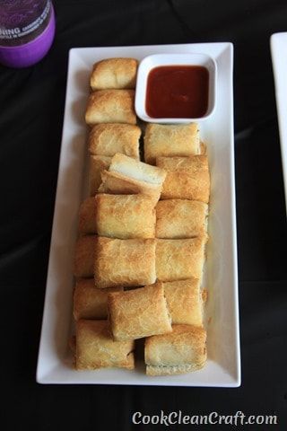 some food is sitting on a white plate with dipping sauce next to it and a bottle of ketchup