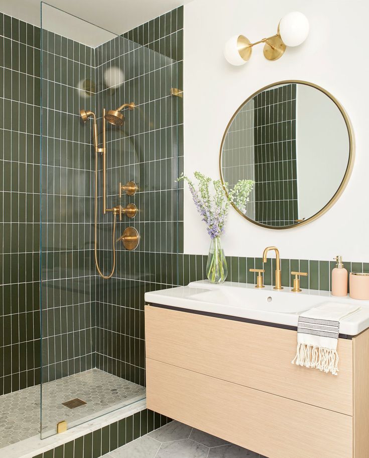 a bathroom with green tile and gold fixtures