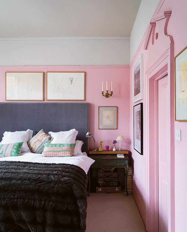 a bedroom with pink walls and pictures on the wall above the bed, along with two nightstands