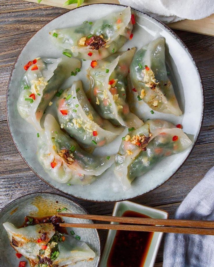 a plate filled with dumplings next to chopsticks and sauce